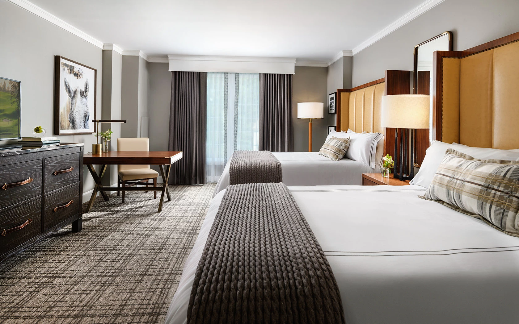 A hotel room with two beds, a desk, and a dresser.