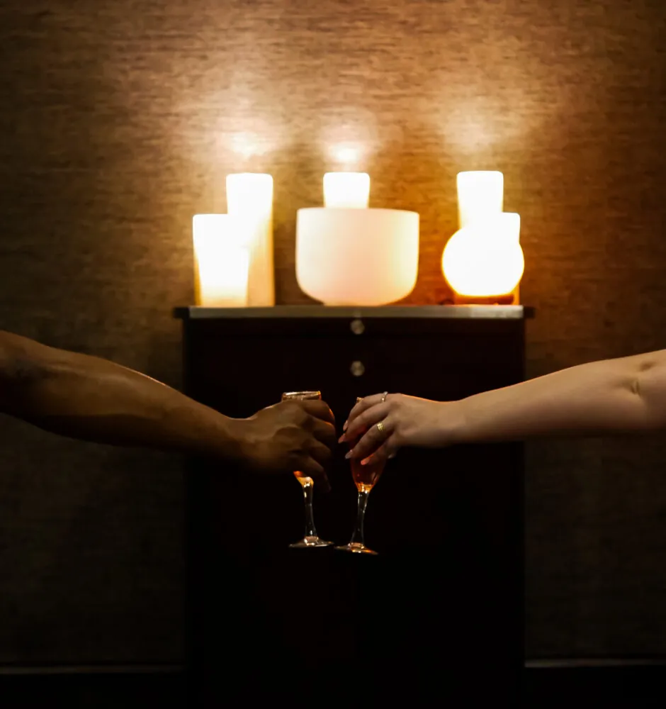 Two hands toasting with champagne in candlelit room