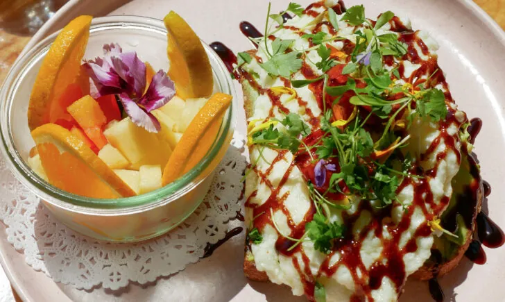 Plate with salad and fresh fruit cup on wooden table
