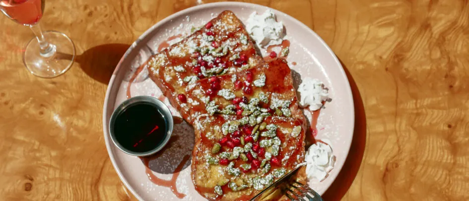 Pancakes topped with cream and fruit on plate