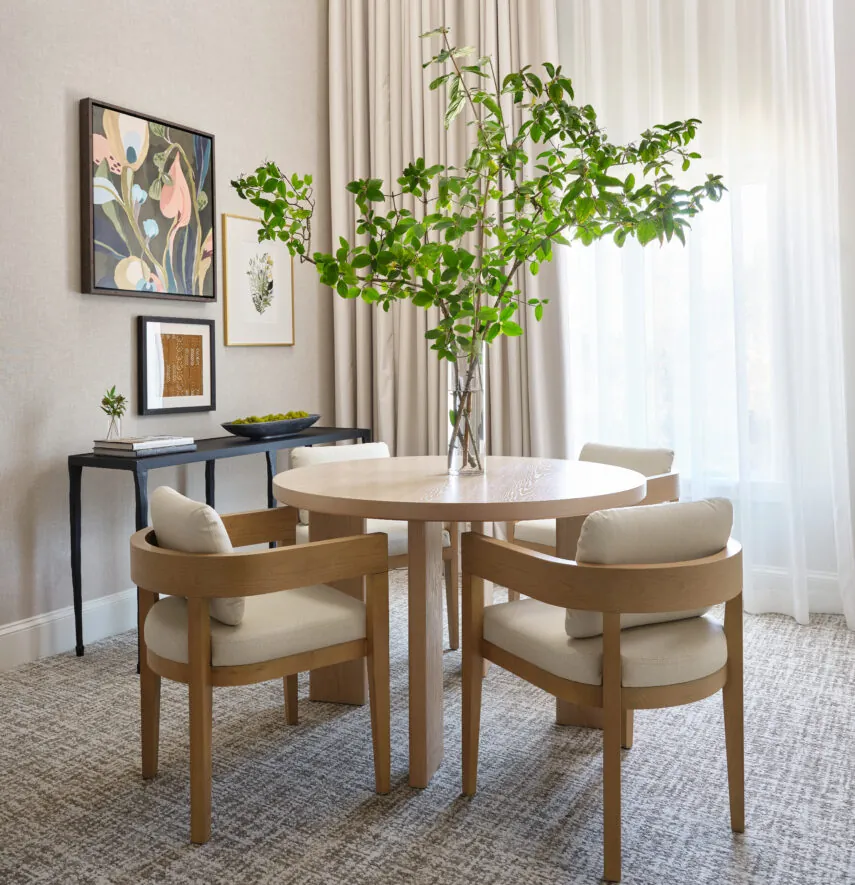 Dining table with chairs and plant in bright hotel room
