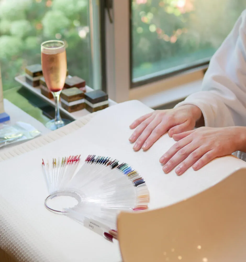 Hands choosing nail polish colors at spa table