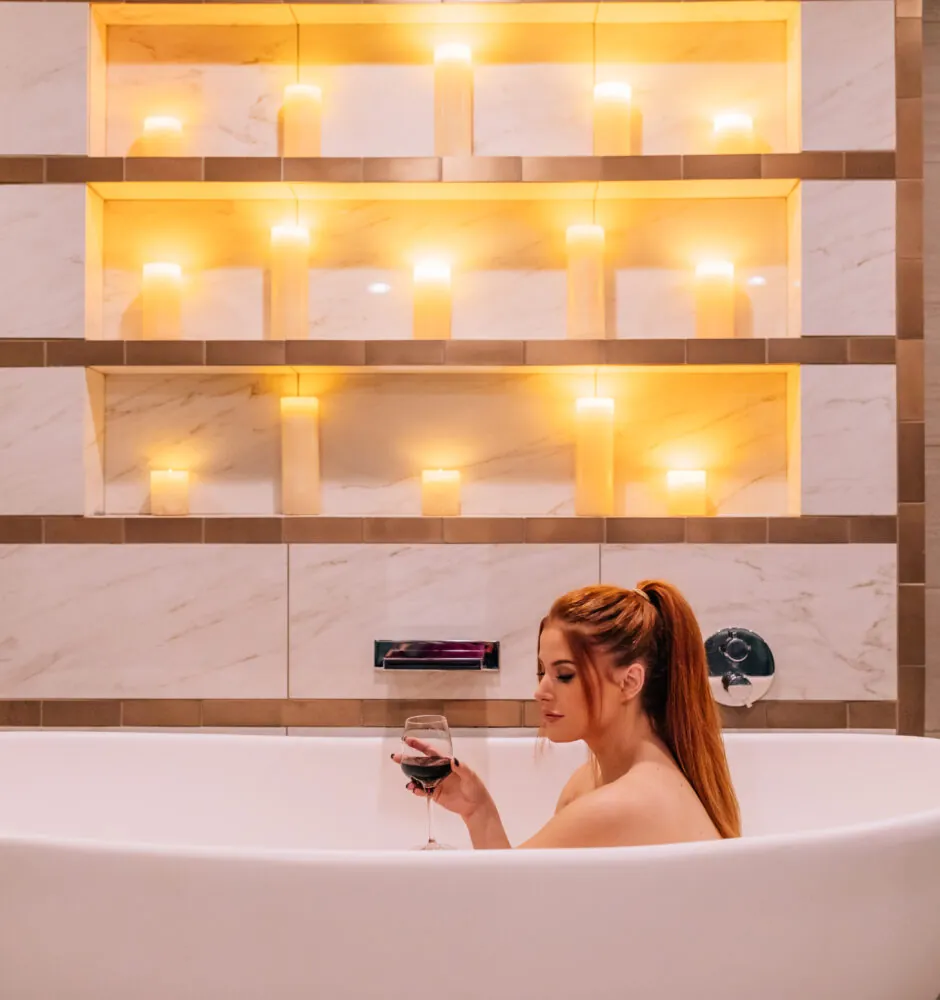 Woman in bathtub with wine glass and candlelight