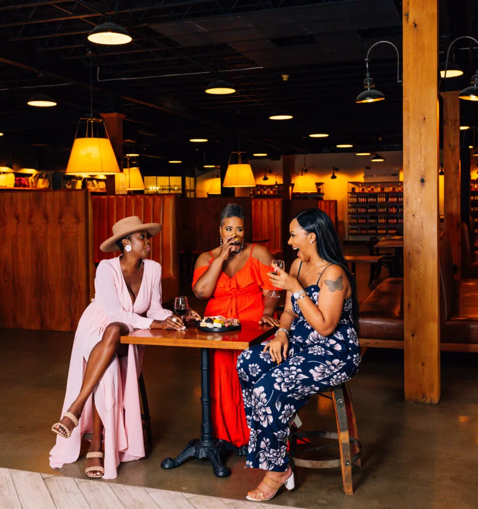 Three women sitting at a table in a cafe, talking and laughing.