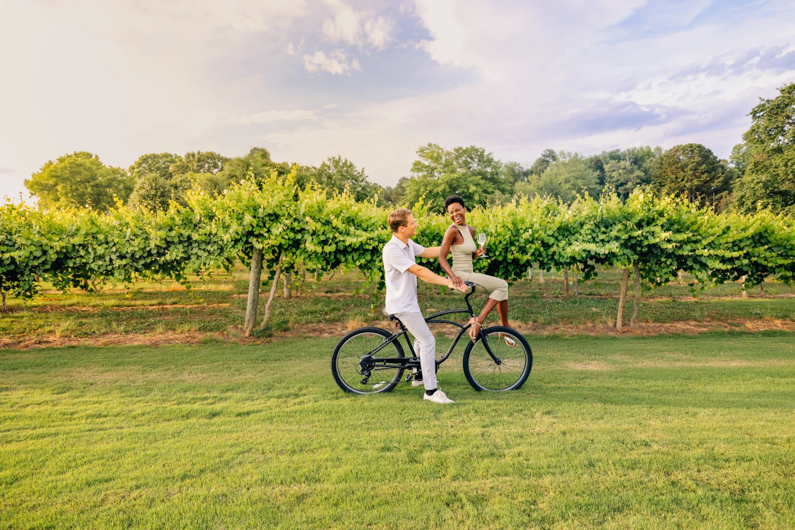 Couple cycling together in vineyard at sunset