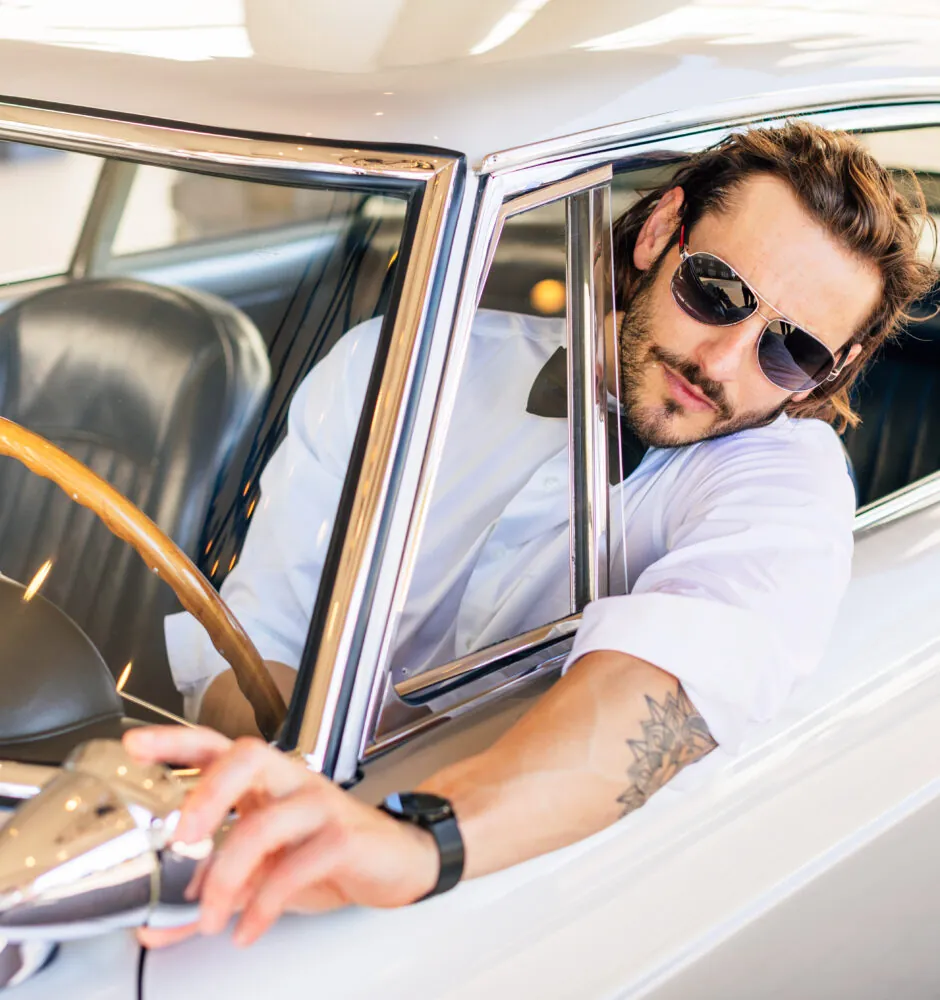 Man in sunglasses driving classic car
