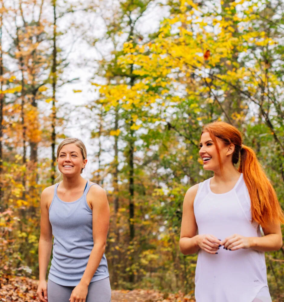 Two women walking on forest trail in autumn