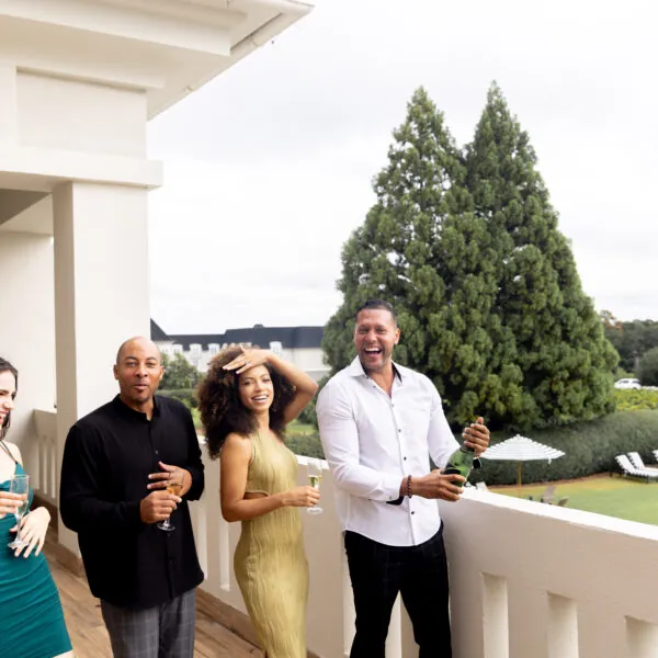 Two couples celebrating with champagne on a balcony.