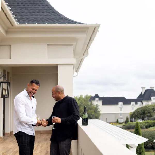 Two men are shaking hands on a balcony.