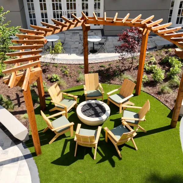 An outdoor area with a fountain, chairs, and a trellis.