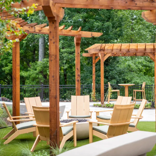 An outdoor patio area with a wooden pergola and chairs.