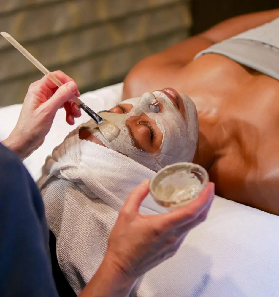 Person receiving facial mask applied with brush
