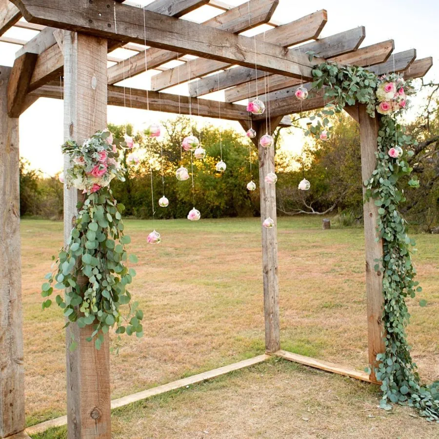 Rustic wooden arch decorated with flowers and greenery.